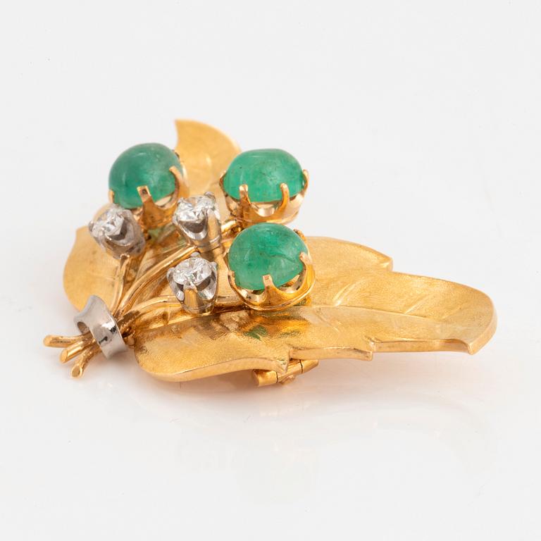 An 18K gold brooch set with emeralds and round brilliant-cut diamonds.