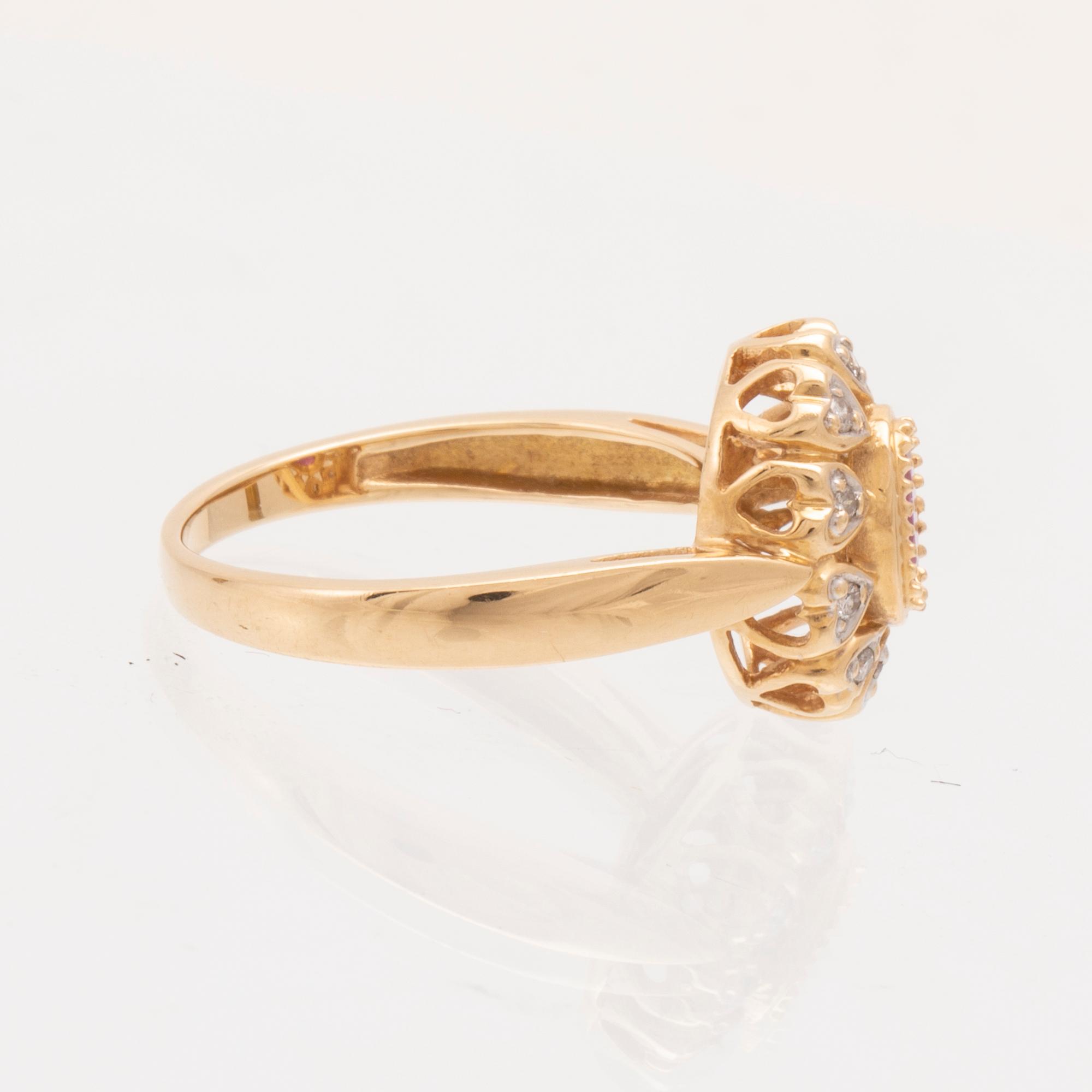 An 18K gold ring set with an oval brilliant cut ruby and round brilliant cut diamonds.
