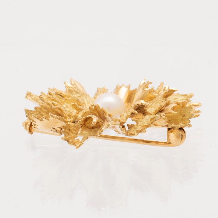 An 18K gold brooch set with a cultured pearl.