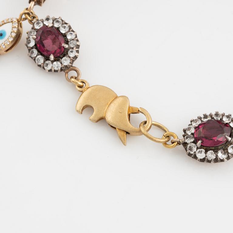 Bracelet with garnets and white stones, two charms, one eye enamel with brilliant cut diamonds, possibly oriental pearl.