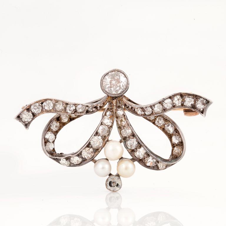 A brooch set with antique- and old-cut diamonds and pearls. The larger diamond approximately 0.50 ct.