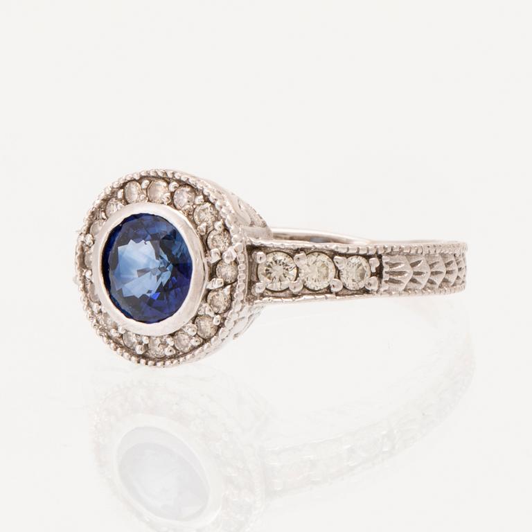 Ring in 18K white gold with a round faceted sapphire and round brilliant-cut diamonds.