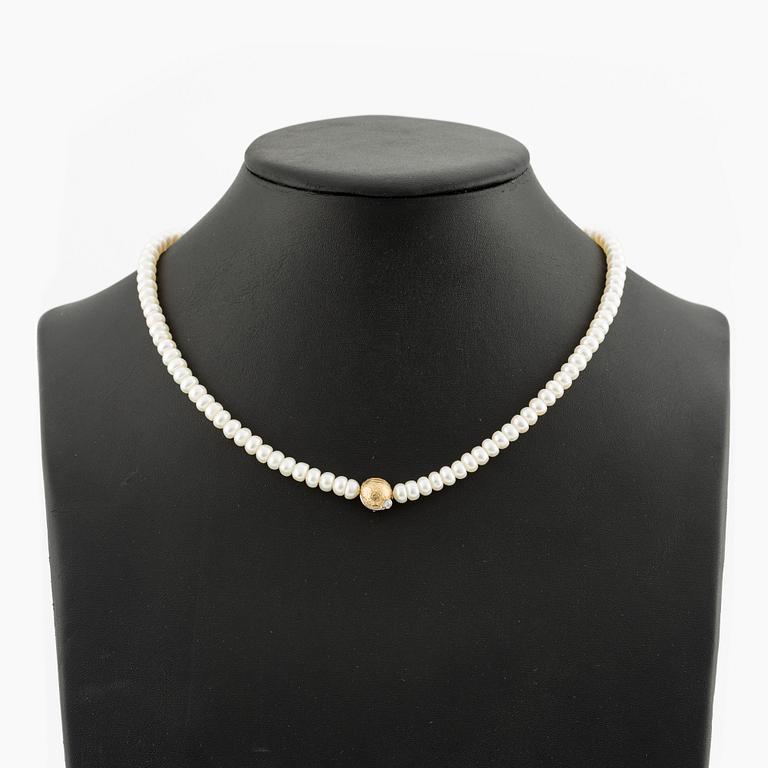 Ole Lynggaard clasp in 18K gold with a round brilliant-cut diamond and a freshwater cultured pearl necklace.