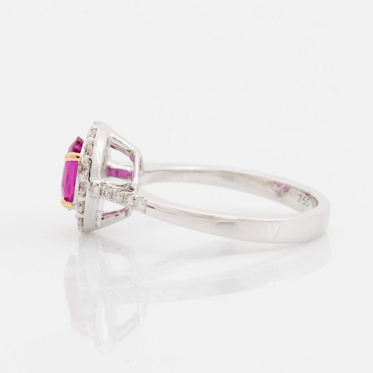 An 18K white gold ring set with a faceted pink sapphire and round brilliant-cut diamonds.