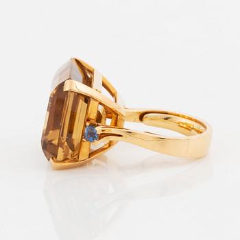 An 18K gold ring set with a faceted citrine and two sapphires.