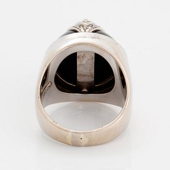 An 18K white gold and onyx ring set with round brilliant-cut diamonds.