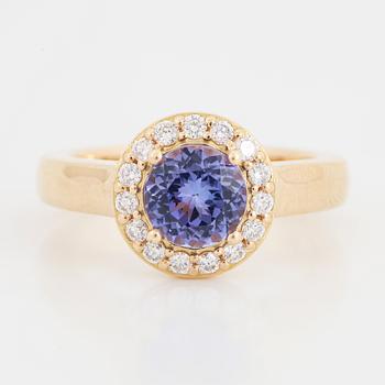 An 18K gold ring set with a faceted tanzanite and round brilliant-cut diamonds.