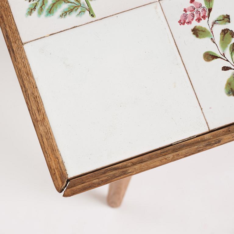 a Swedish Modern coffee table, decorated with Jobs' ceramic tiles, signed and dated 1941.