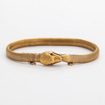 An 18K gold bracelet, in the form of a serpent, eyes set with a garnet and a syntethic ruby. Swedish import mark.