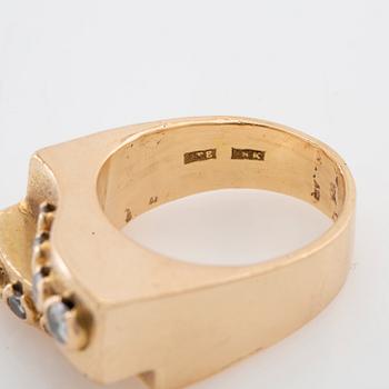 Ring in 18K gold set with round brilliant-cut diamonds and a round faceted gemstone.