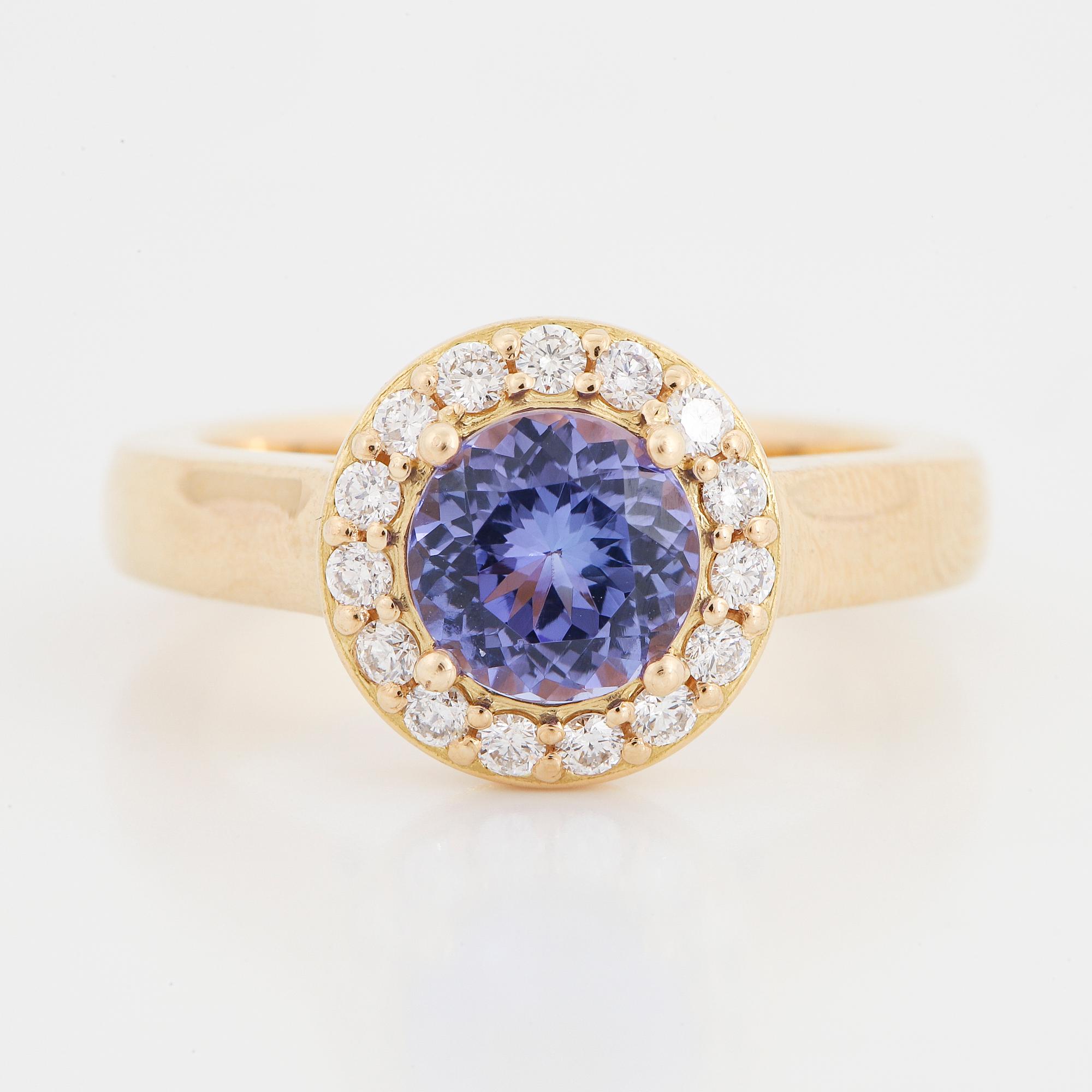 An 18K gold ring set with a faceted tanzanite and round brilliant-cut diamonds.