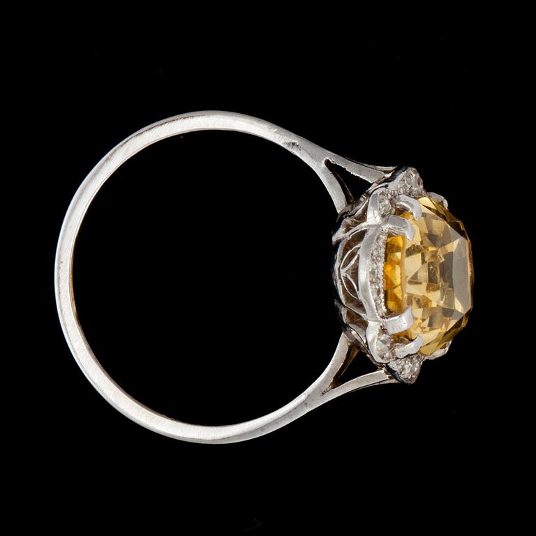 A ring with a yellow sapphire circa 9.40 cts surrounded by old-cut diamonds.