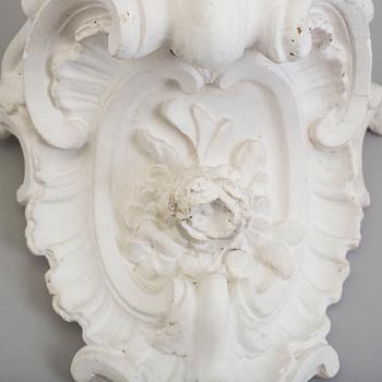 A pair of consoles and a set of three decor-elements, plaster, 20th century.