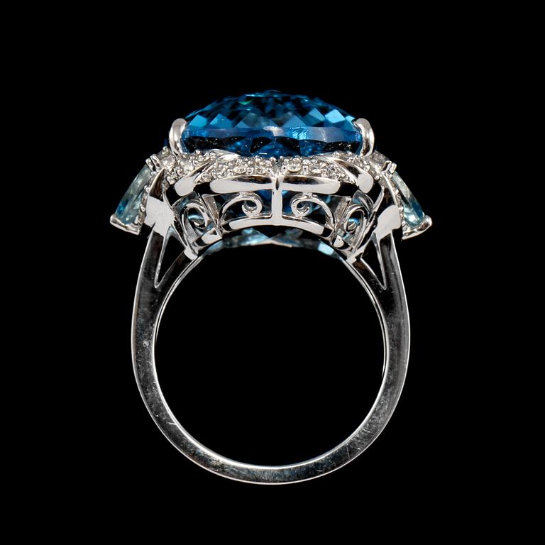 RING, 18k vitguld med checkerslipad blå topas, 2 fasettslipade akvamariner och 68 briljantslipade diamanter. Vikt 14g.