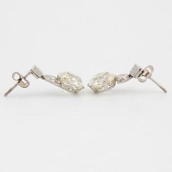 A pair of platinum earrings set with cushion formed old-cut diamonds with a total weight of ca 6.00 cts quality ca L/M v.