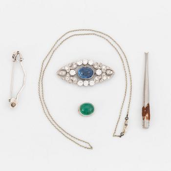 A platinum brooch set with a cabochon-cut sapphire and a cabochon-cut emerald.