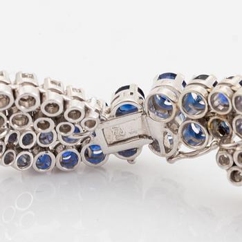 An 18K white gold bracelet set with round brilliant-cut diamonds and sapphires.