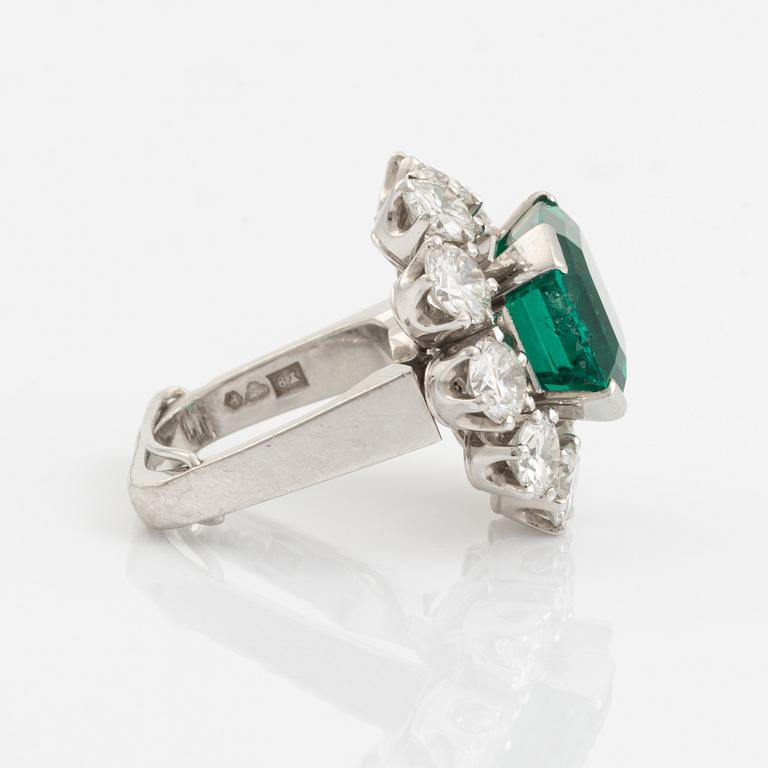 A WA Bolin platinum ring set with a step-cut emerald and round brilliant-cut diamonds.