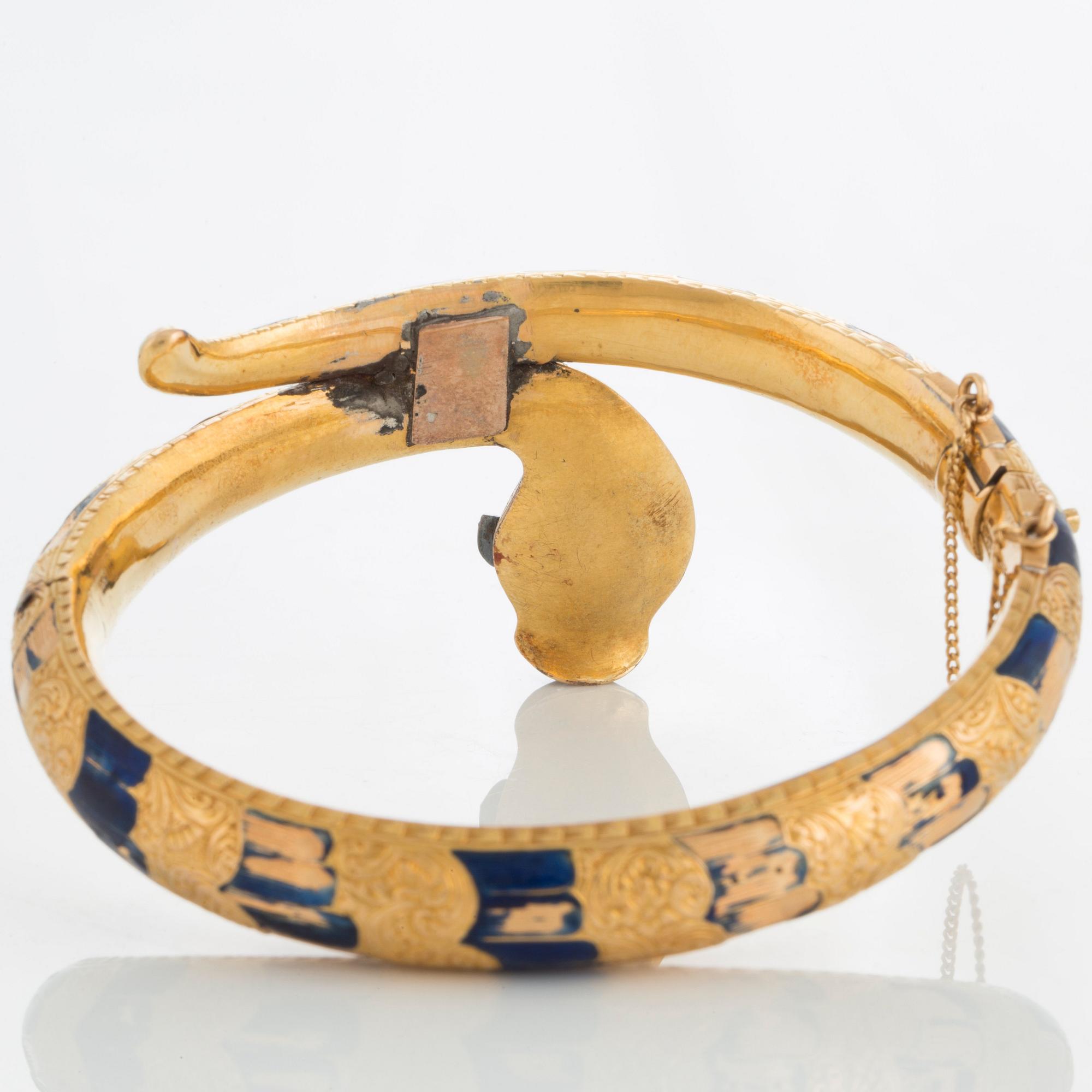 An 18K gold snake bangle decorated with blue enamel and set with an opal and a rose-cut diamond.