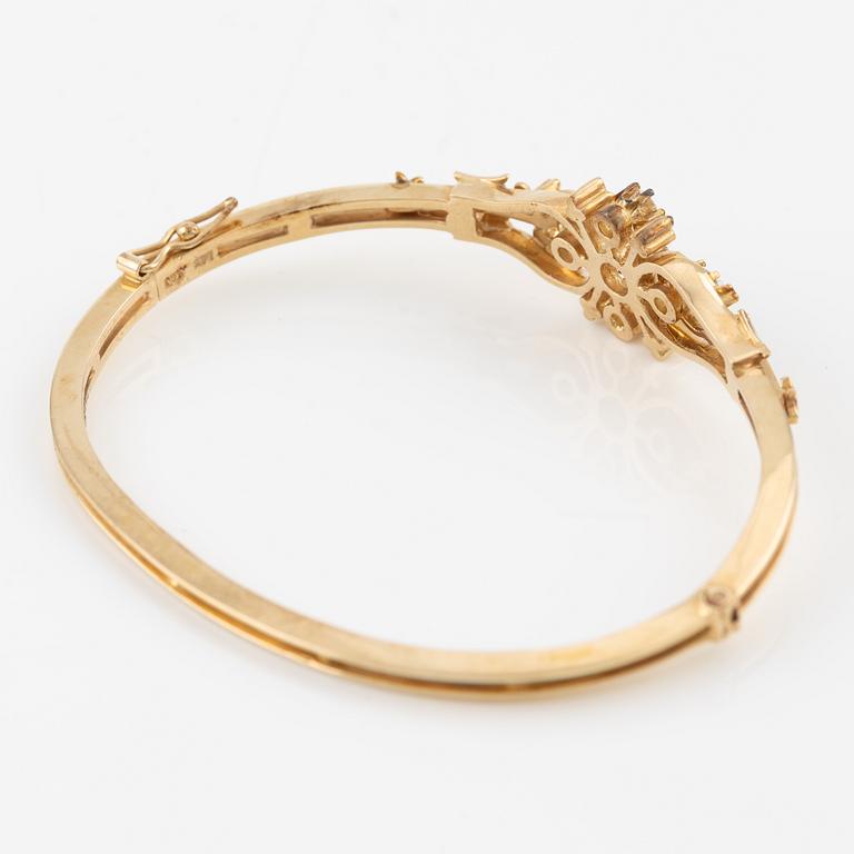 A bangle in 14K gold with round brilliant-cut diamonds.