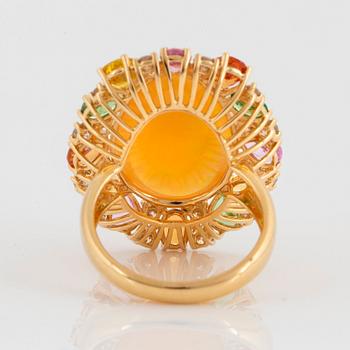 An 18K gold ring set with an opal, round brilliant-cut diamonds.