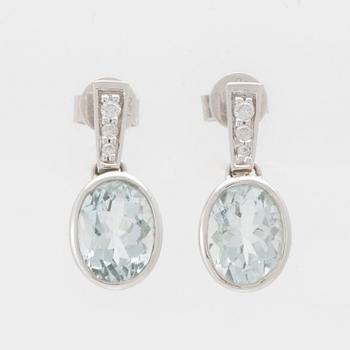 A pair of 18K white gold earrings set with oval faceted aquamarines and round brilliant-cut diamonds.