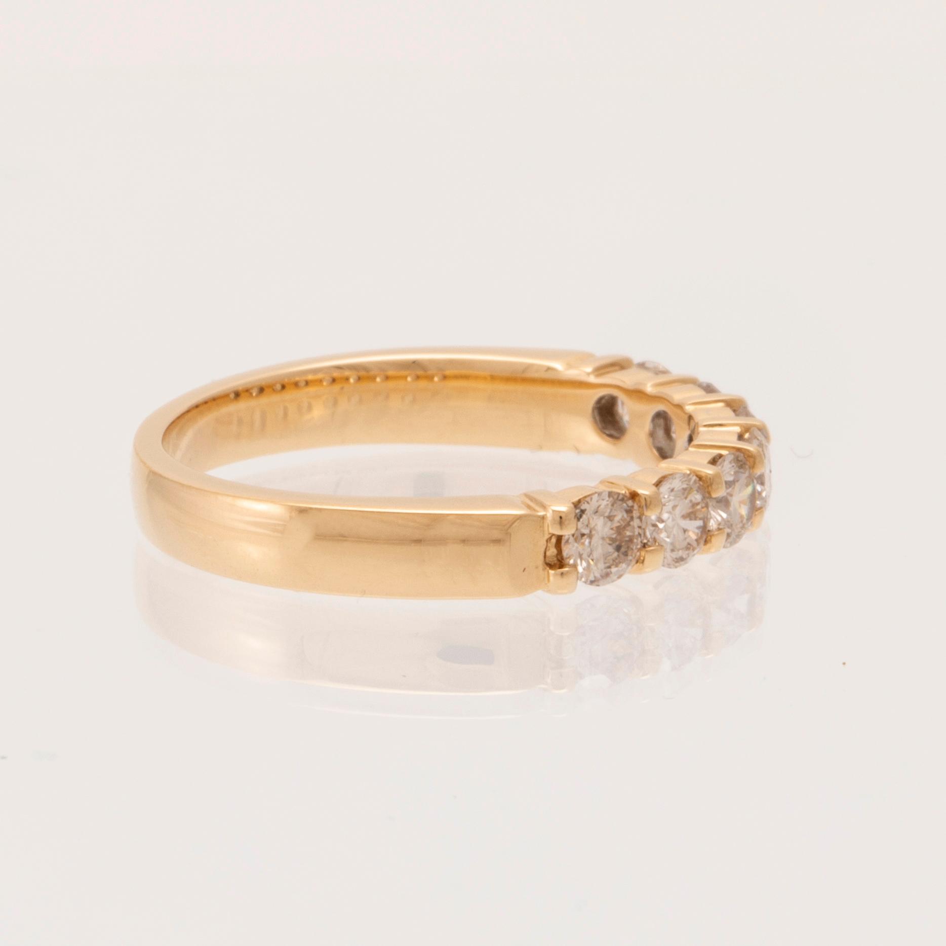 An 18K gold half-eternity ring set with round brilliant-cut diamonds.