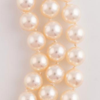 A three strand cultured pearl necklace with an 18K gold clasp set with round brilliant-cut diamonds.