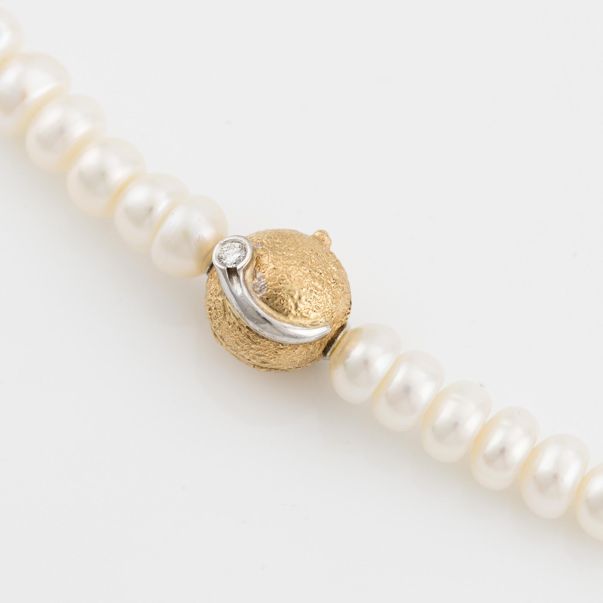 Ole Lynggaard clasp in 18K gold with a round brilliant-cut diamond and a freshwater cultured pearl necklace.
