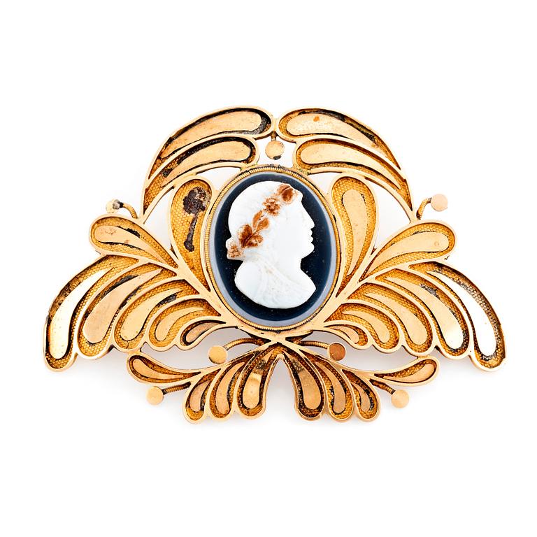 An 18K gold brooch set with a hard stone cameo.