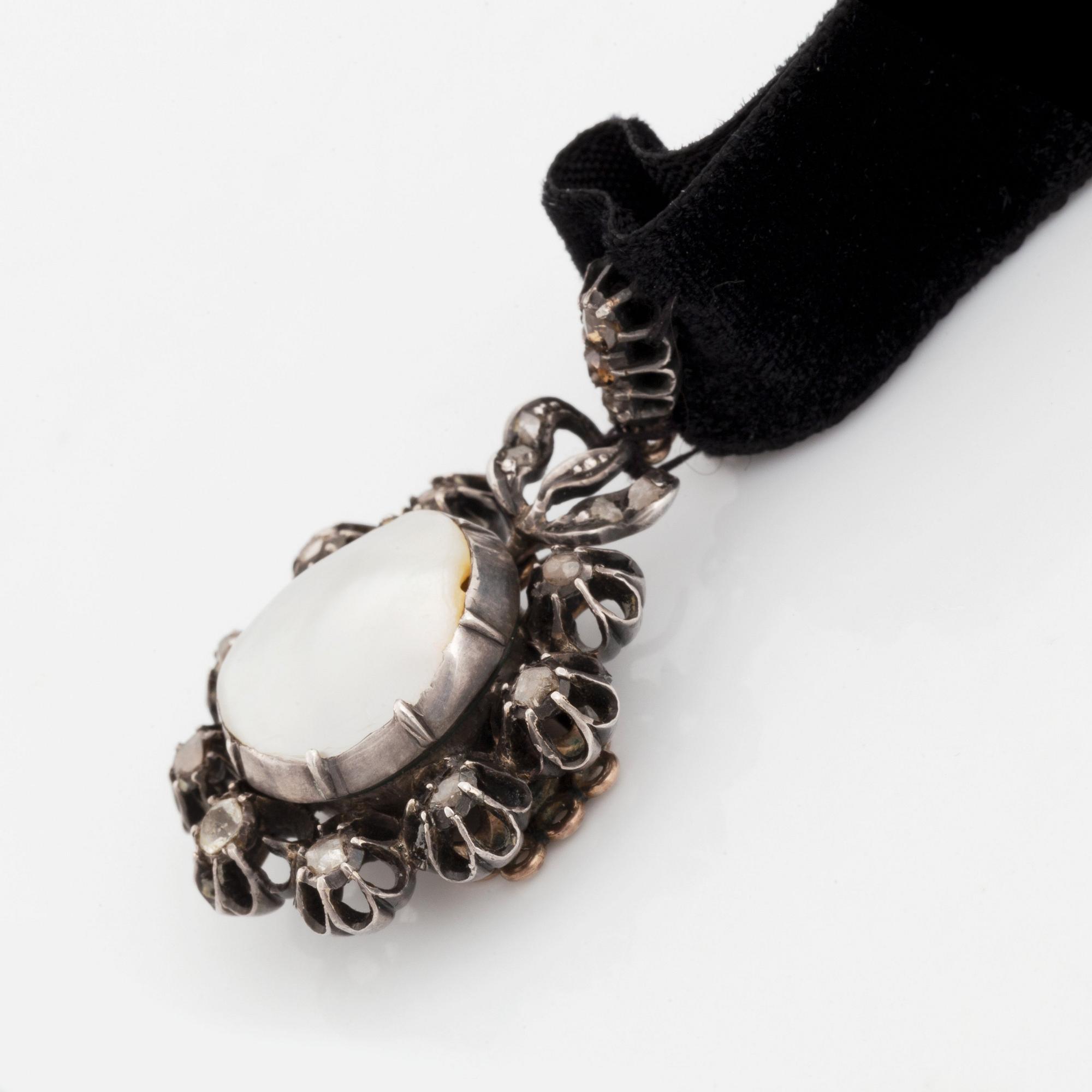 A silver pendant with a pearl and rose-cut diamonds.