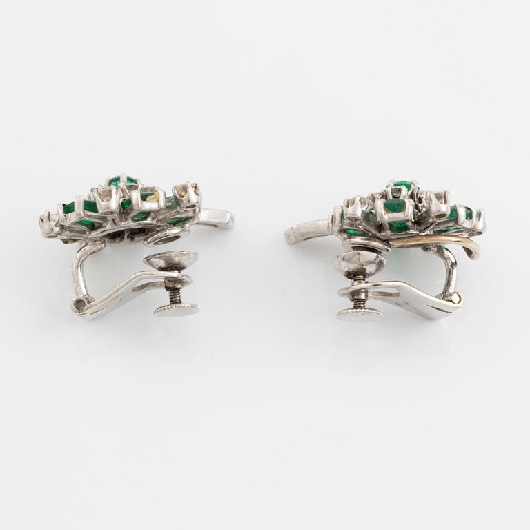 A pair of 14K white gold, emerald and round brilliant- and baguette cut diamond ear clips.
