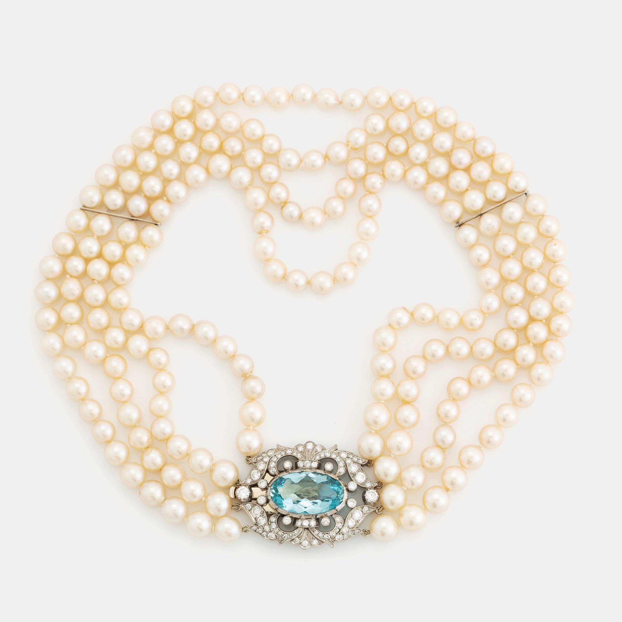 A four strand cultured pearl necklace with a clasp in 14K gold set with a faceted aquamarine.
