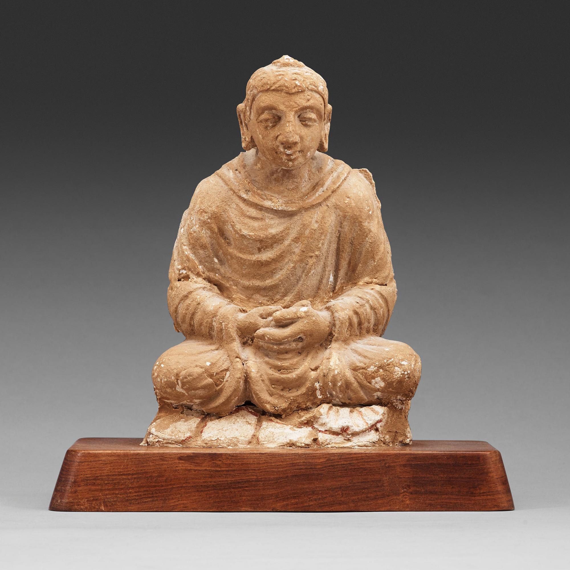 A stucco figure of a seated buddha, Gandhara, 2nd/3rd Century.