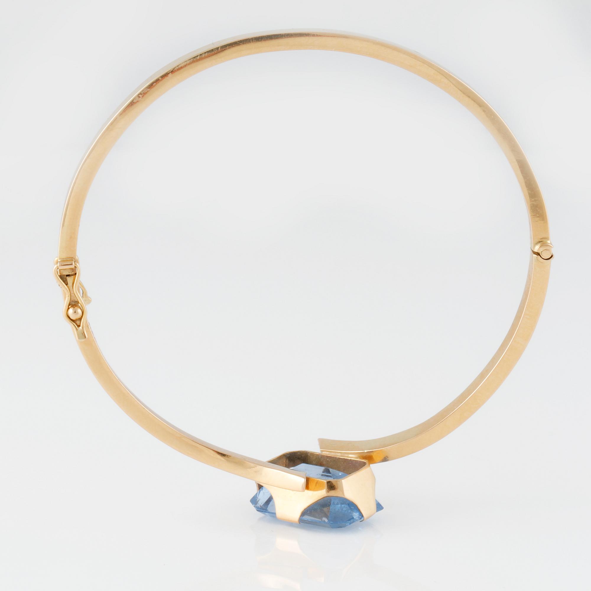 ARMRING, 18K guld med fasettslipad syntetisk blå spinell, Svenskt Guldsmide, Stockholm, 1956. Vikt 9,8 gram.