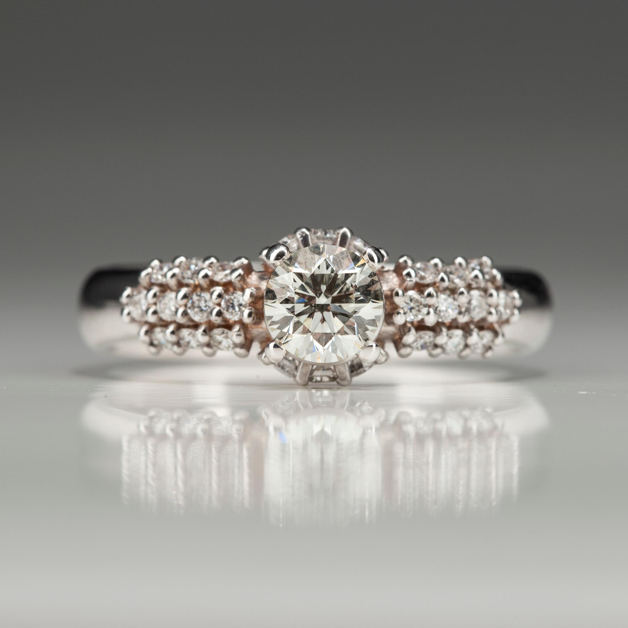 RING, vitguld 18K med diamanter. Mittstenen 0,52 ct L/SI1. 26 små diamanter tot 0,35 ct H/SI1. Intyg.