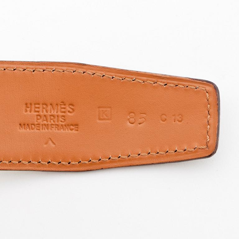 HERMÈS, a green crocodile belt with silver colored H belt buckle.