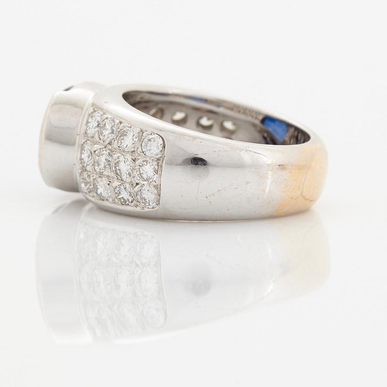 An 18K white gold ring set with an oval faceted sapphire and round brilliant-cut diamonds.