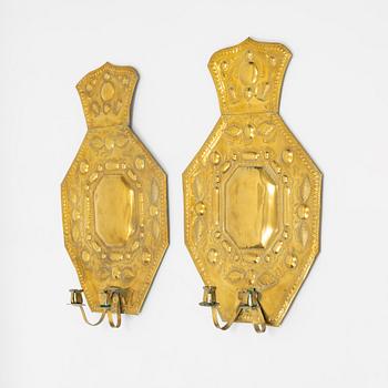 A pair of Baroque style brass wall sconces form around the year 1900.