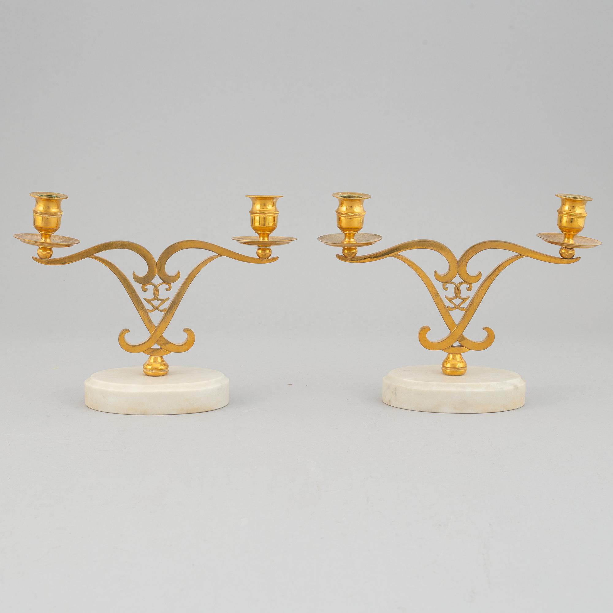 A pair of brass candle sticks om marble stands from the middle of 20th century.