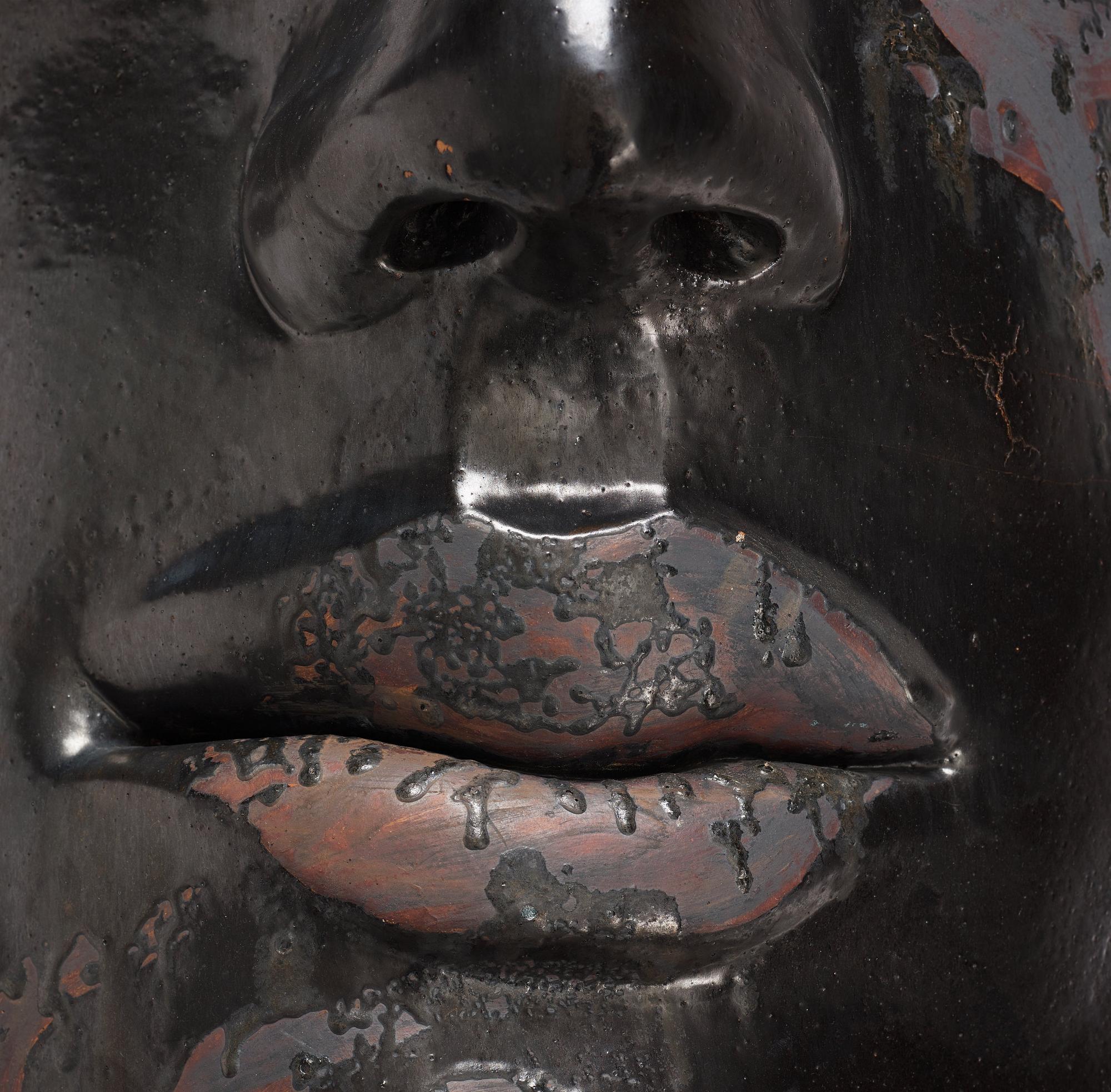 Hertha Hillfon, a black glazed stoneware wall sculpture in two parts of a face and a sky, executed in her own studio, Stockholm 1960s.