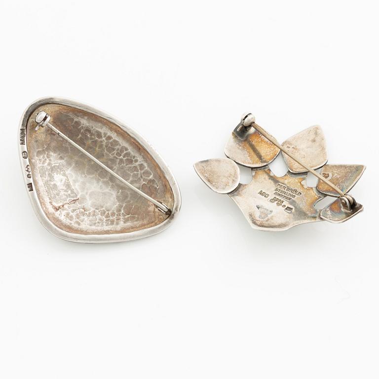 Två broscher, silver och stenar.
