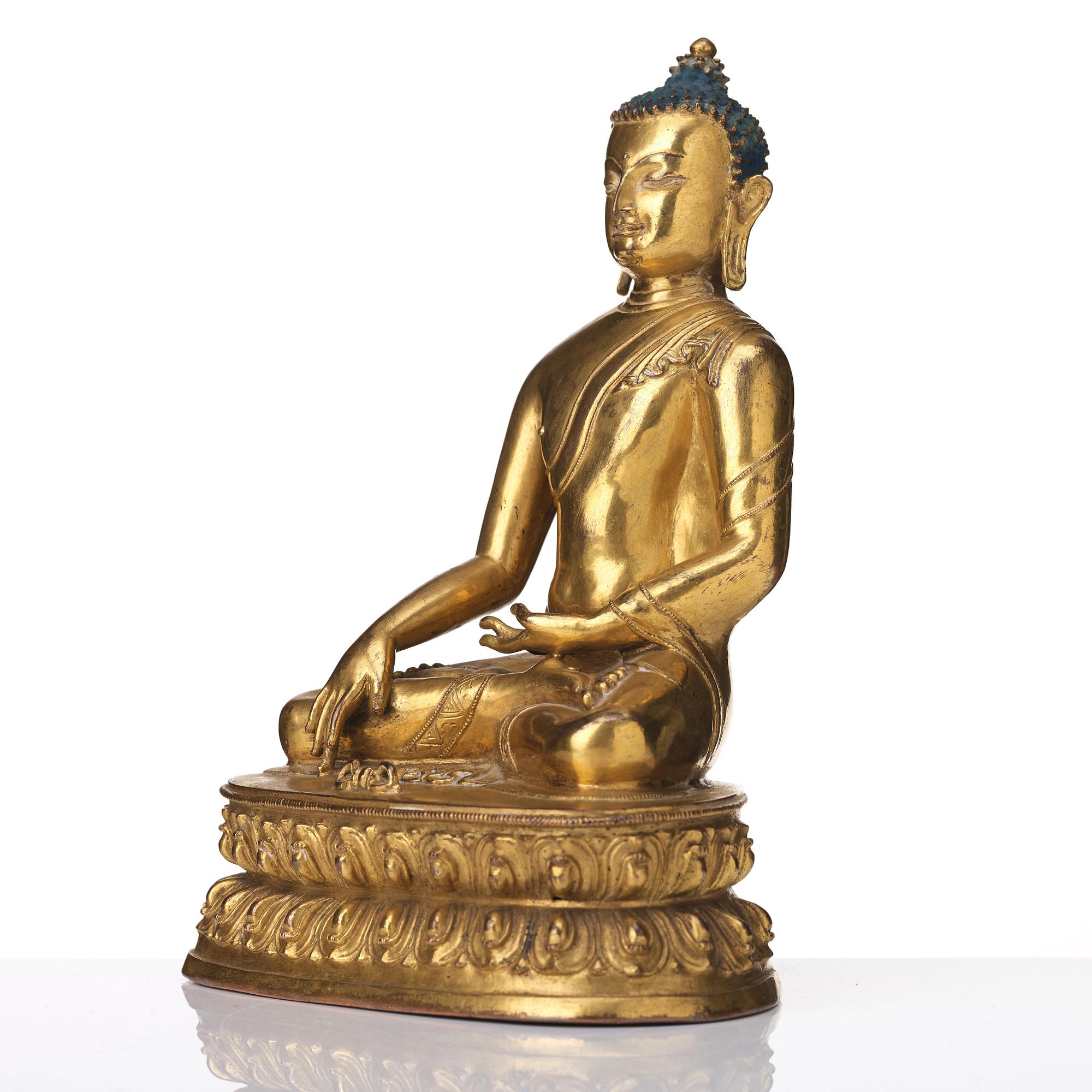 A gilt copper alloy figure of Akhsobya buddha, Tibet, 15th Century.