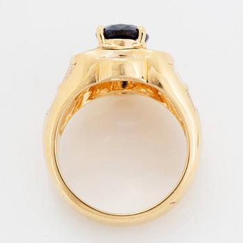 An 18K gold Junod ring set with a facted sapphire and tapered baguette-cut diamonds.