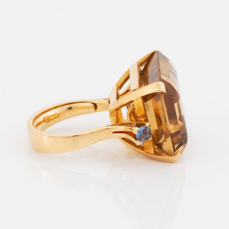 An 18K gold ring set with a faceted citrine and two sapphires.