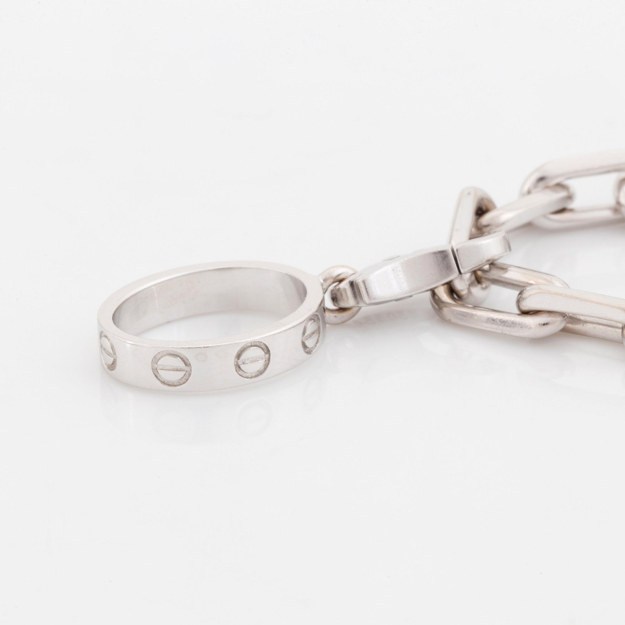 An 18K white gold Cartier "Spartacus" bracelet with two charms.