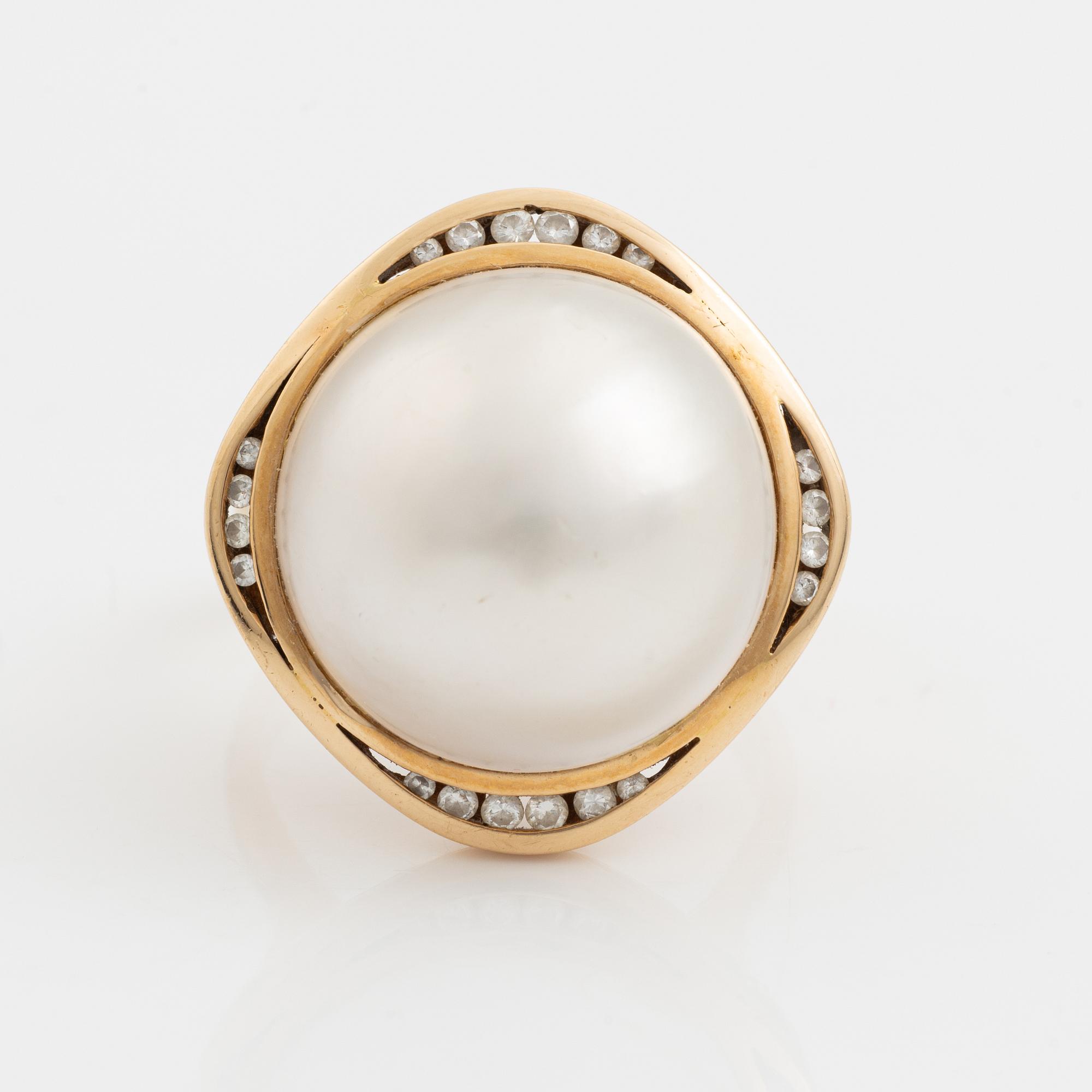 A 14 k gold ring set with a half pearl and round brilliant-cut diamonds.