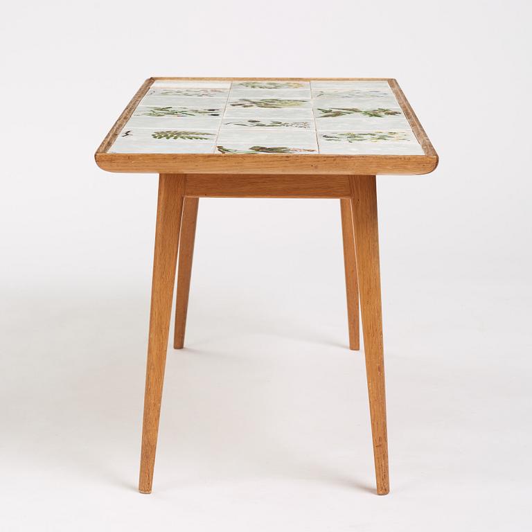 a Swedish Modern coffee table, decorated with Jobs' ceramic tiles, signed and dated 1941.