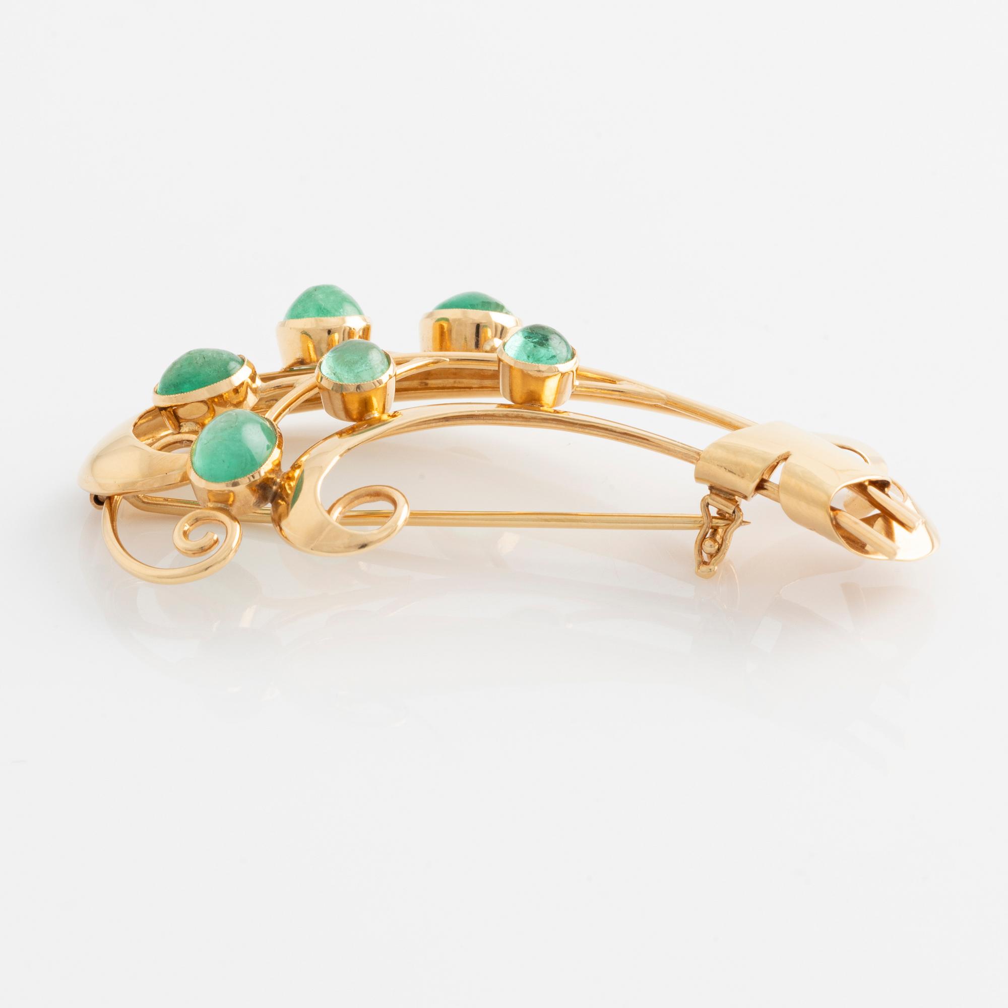 Brooch in 18K gold set with cabochon-cut emeralds.