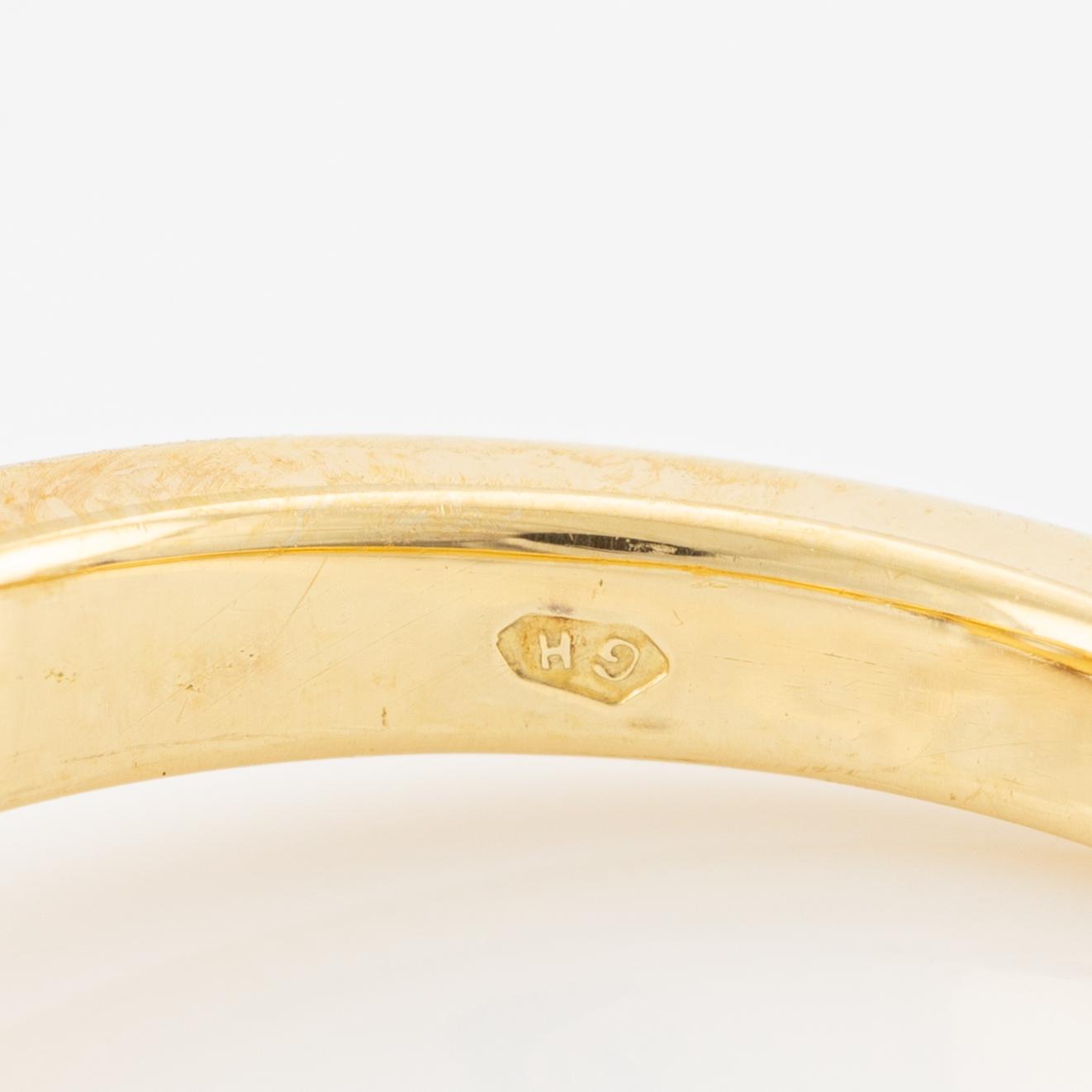 A ring in 18K gold with an oval brilliant-cut diamond and two round brilliant-cut diamonds.